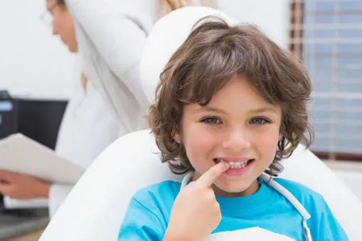 young boy at dental office pointing to tooth